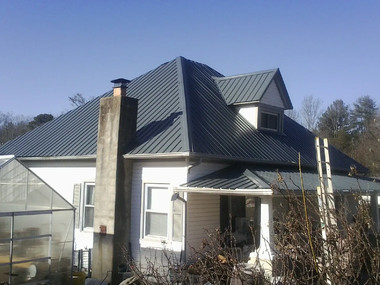 Dark blue standing seam metal roof on a white farmhouse with dormer — Slate & Tile Roof Repair by Roofing Brothers in Joseph City