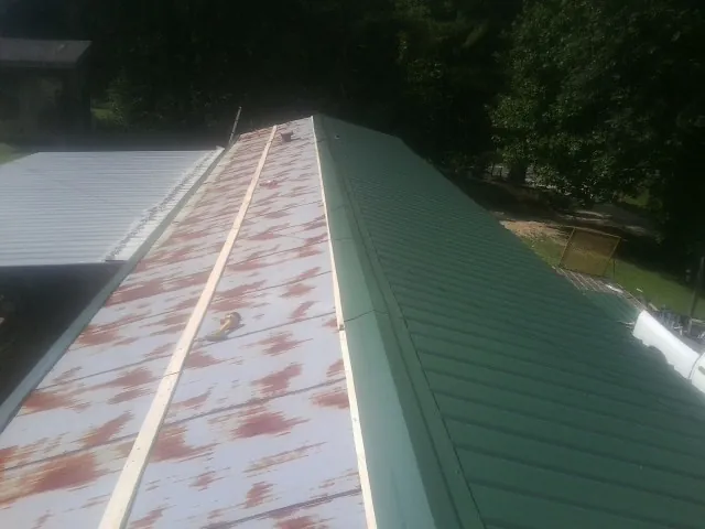 Old rusted panels beside newly installed green metal roofing — Wind Damage Roof Repair by Roofing Brothers in Joseph City
