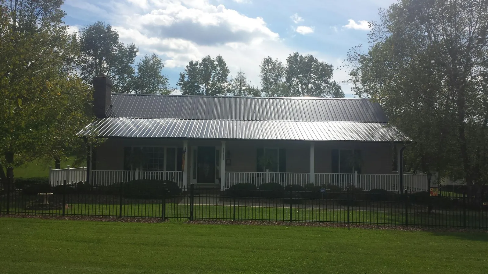 Gray metal roof on a brick ranch with a full width front porch — Gutter Guard Installation work by our crew in Joseph City