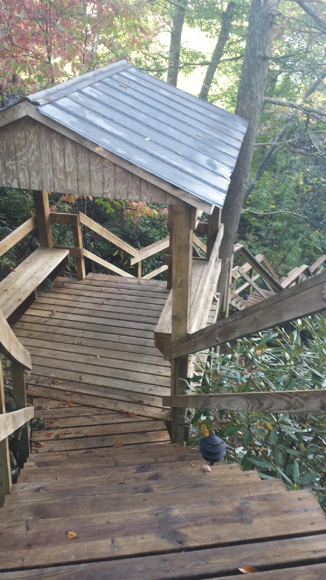 Metal roofed shelter over wooden steps on a wooded walkway — Skylight Repair & Installation work by our crew in Joseph City