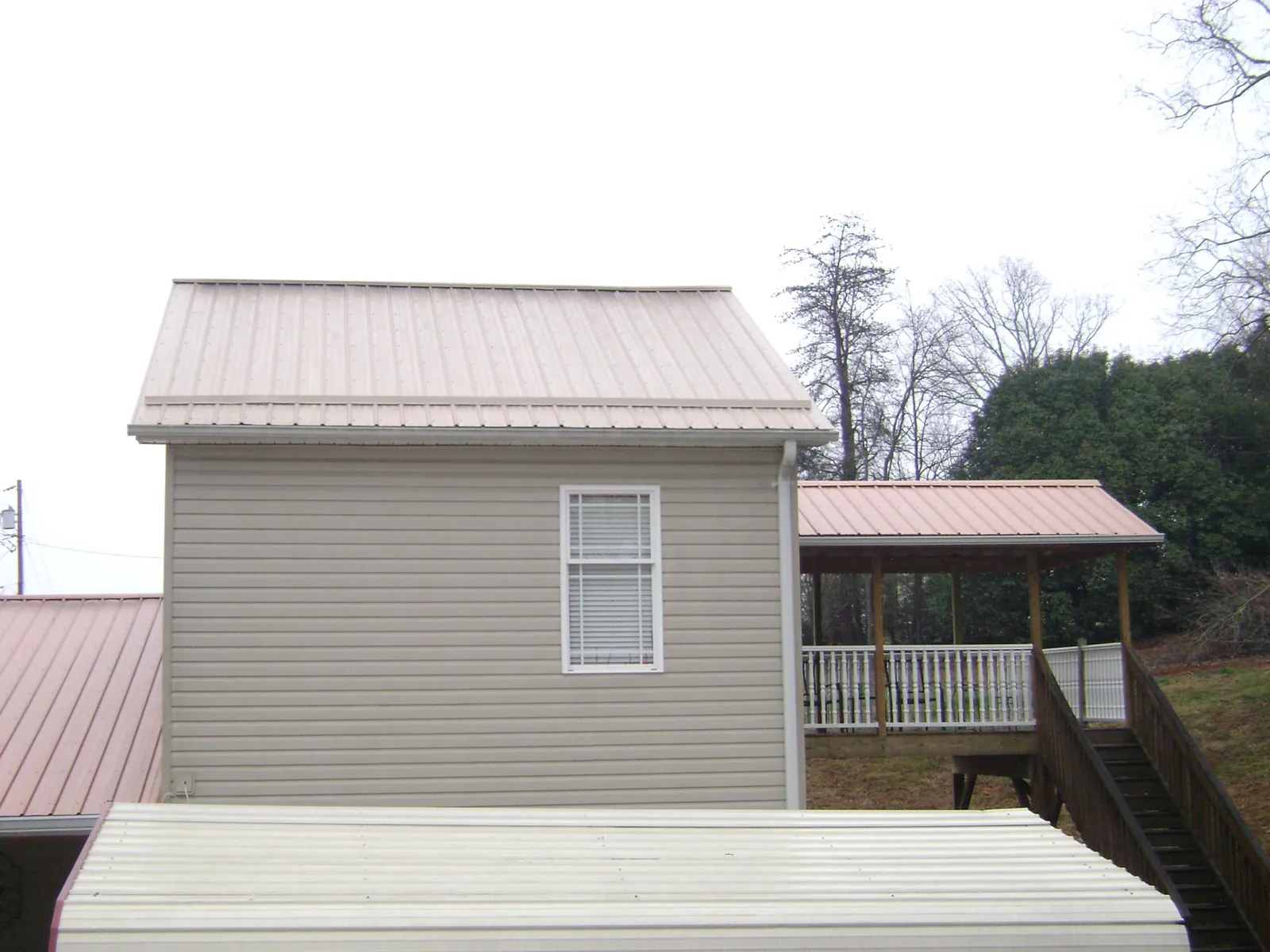 Tan metal roofs on a two story addition and attached porch, from a Roof Replacement job in Joseph City