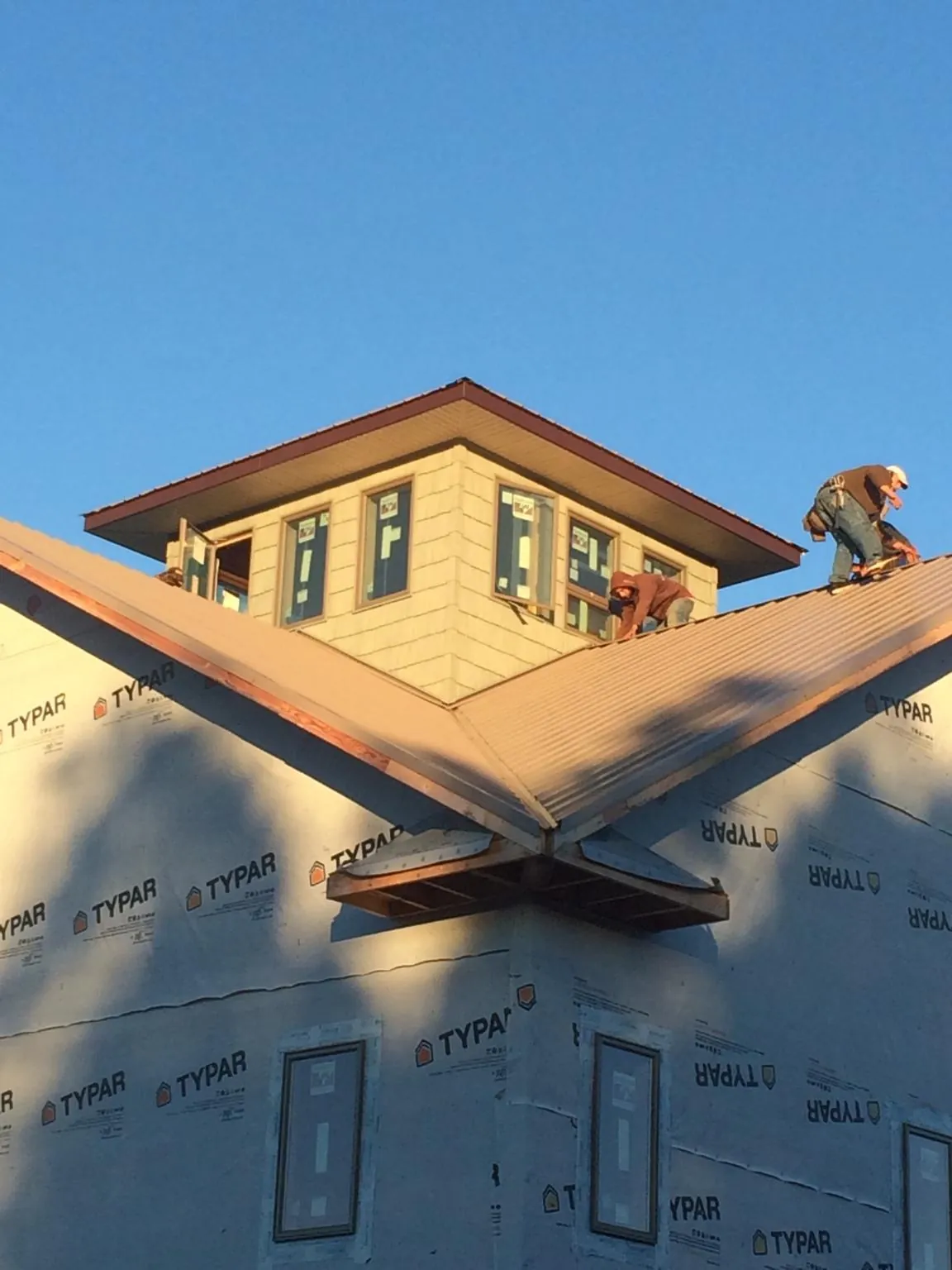Roofers working around a rooftop cupola on a new metal roof at sunset — Roof Waterproofing in Joseph City by Roofing Brothers